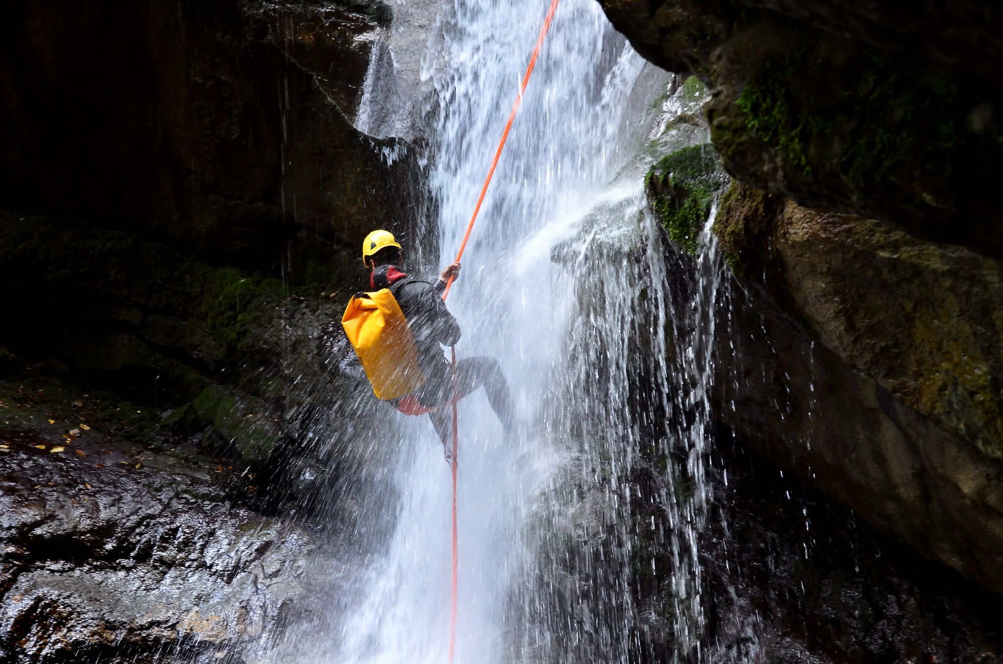 Person canyoning down a waterfall Person canyoning down a waterfall
