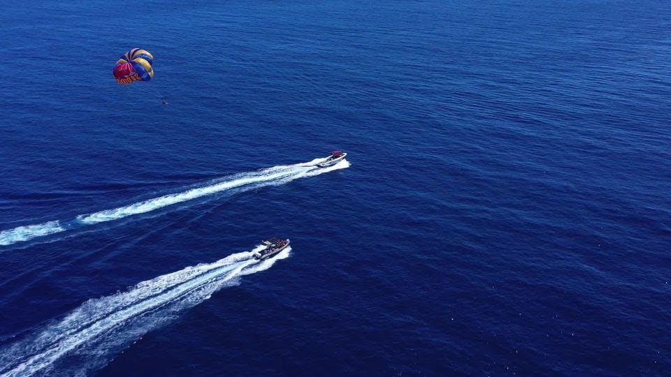 ParaSail Vue panoramique sur une eau bleue avec deux bateaux et un parachute ascensionnel.