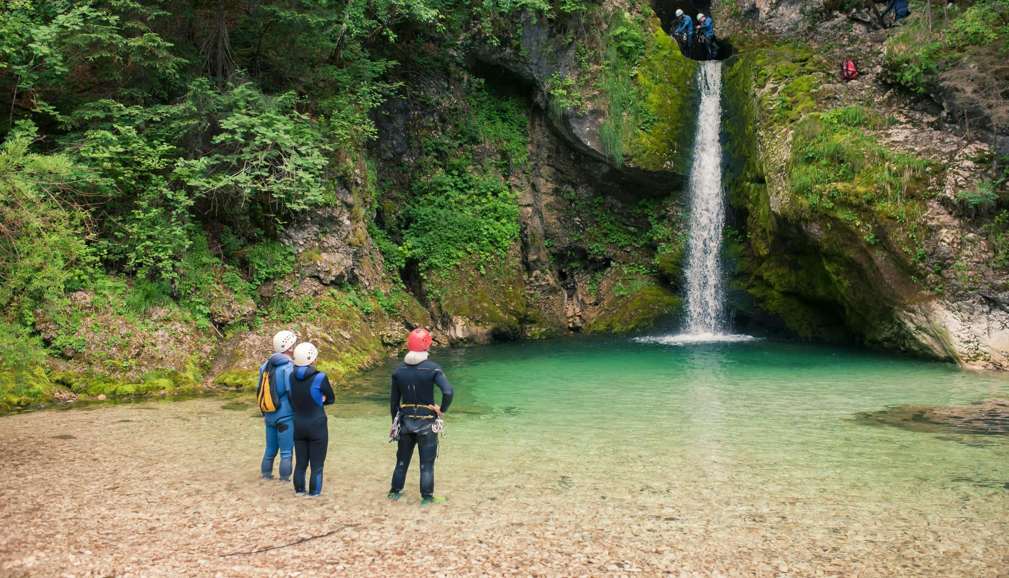 3glav Adventures Bled Die Teilnehmer einer Canyoning-Tour mit 3glav Adventures stehen vor einem tosenden Wasserfall im Triglav-Nationalpark.