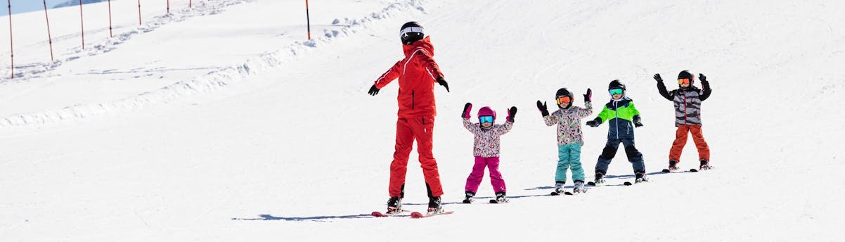 Neue Regionen SEM Hero 1 Skilehrer und Kinder fahren während eines Skikurses die Pisten hinunter.