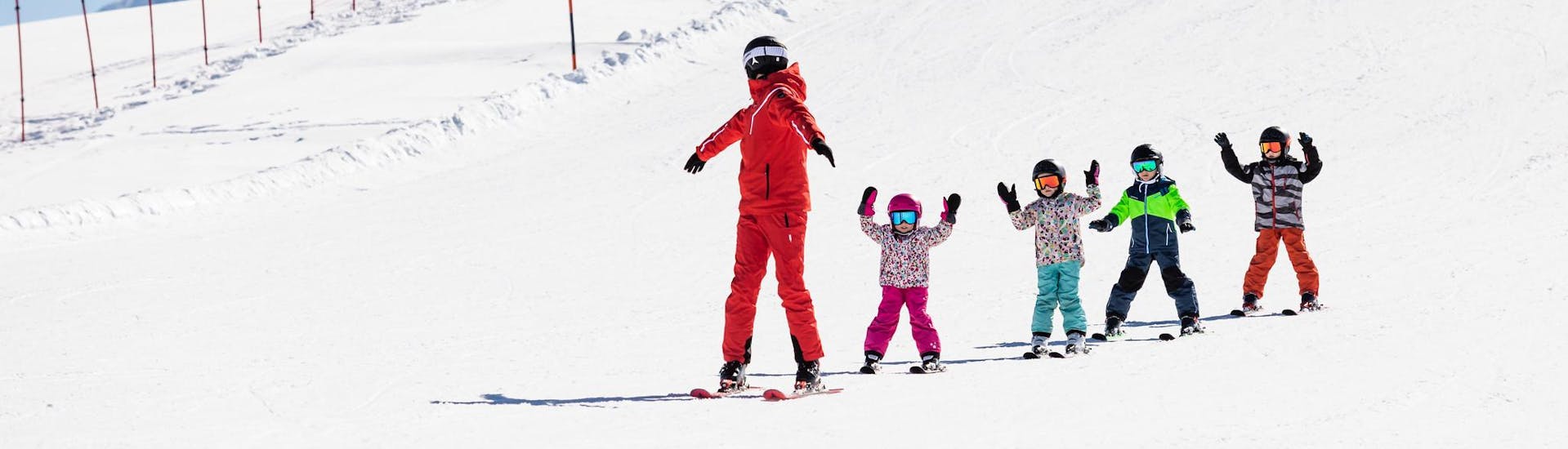 Maestro di sci e bambini si godono una lezione di sci con una scuola di sci vicino a Milano.