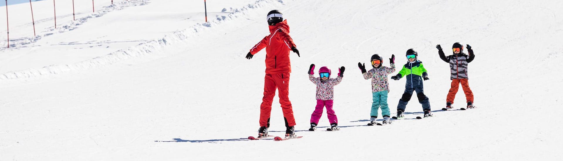 Ski instructor and kids enjoy a ski lesson with a ski school near Sierre.