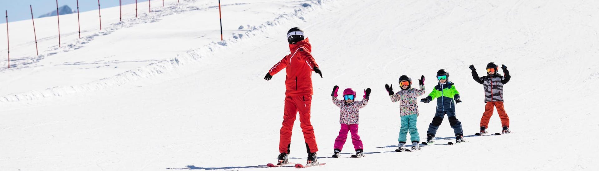 Skilehrer und Kinder fahren während eines Skikurses die Pisten hinunter.