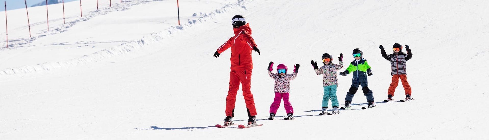 Ski instructor and kids skiing down the slopes during a ski lesson.
