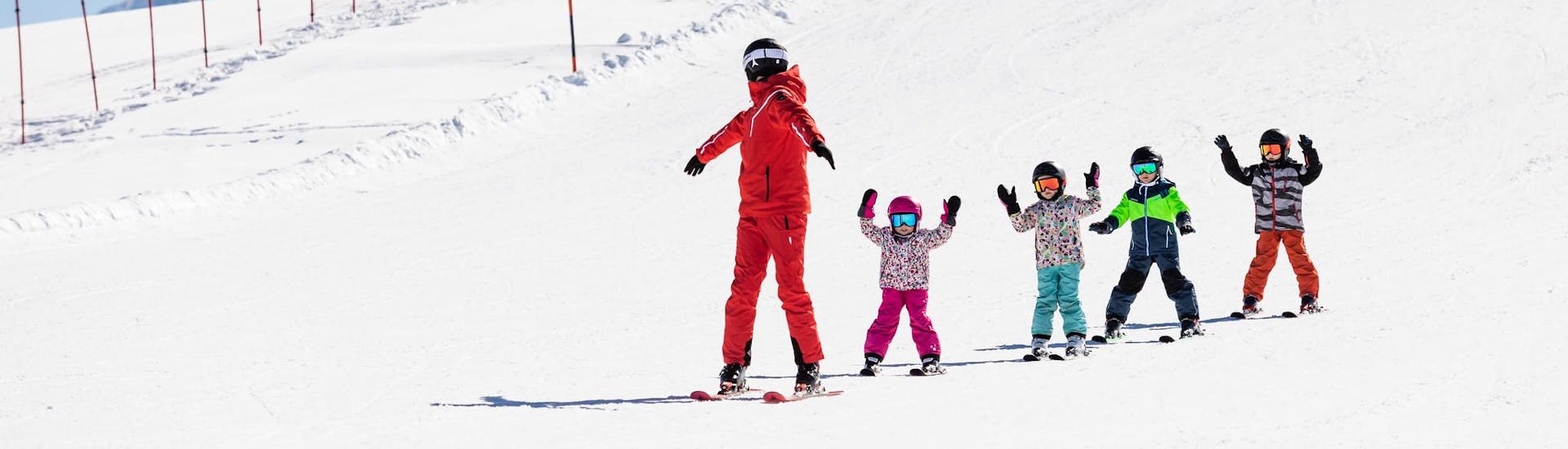 Skileraar en kinderen skiën de piste af tijdens een skiles.
