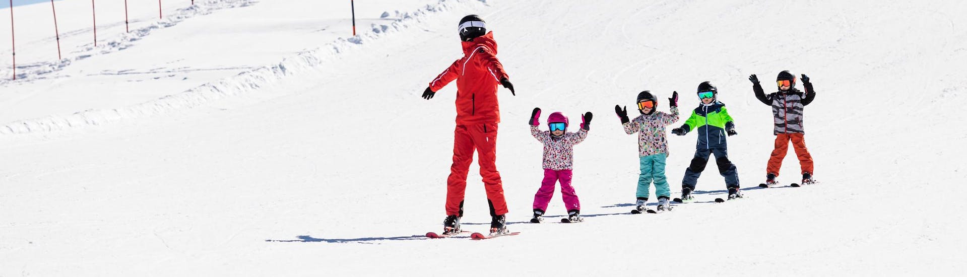 Ski instructor and kids skiing down the slopes during a ski lesson.
