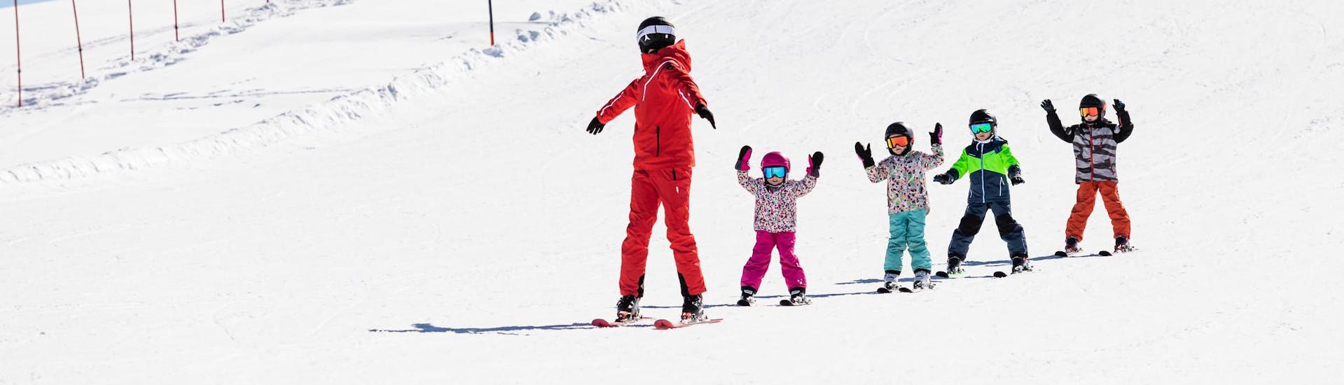 Skileraar en kinderen skiën de piste af tijdens een skiles.