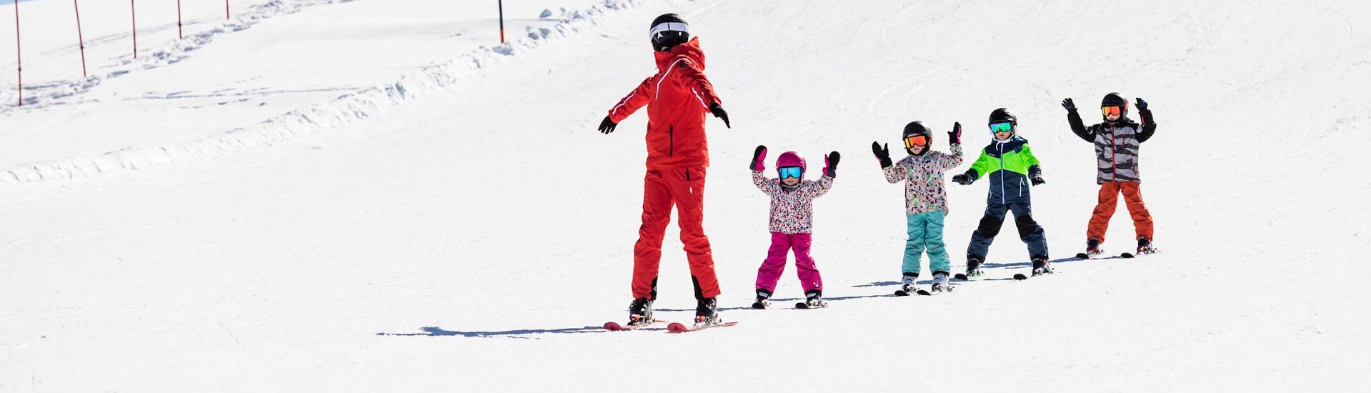 Skilehrer und Kinder fahren während eines Skikurses die Pisten hinunter.