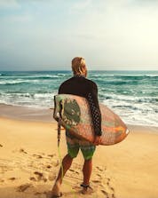 Surfeur à la mer debout avec une planche de surf couleur vive.