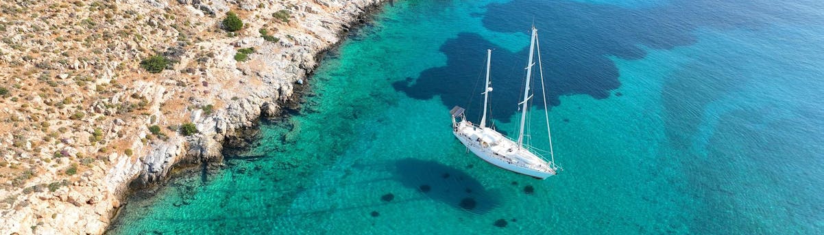Boat Trips Saint-François SEM Hero Vue aérienne d'un voilier glissant sur la mer bleue claire sous un ciel lumineux.