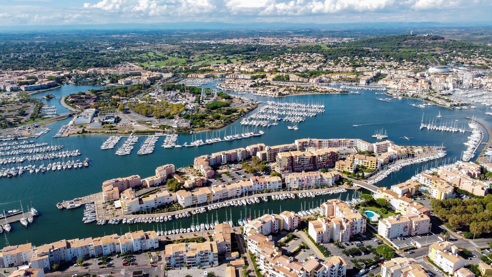 Vue panoramique du Agde avec des bateaux et la ville côtière en arrière-plan.