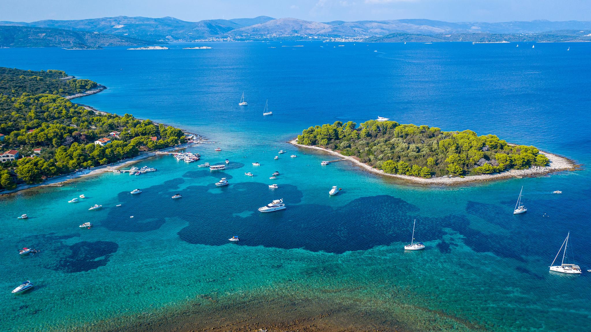Boote treiben auf dem kristallklaren, türkisfarbenen Wasser der Blauen Lagune in Kroatien, umgeben von natürlicher Schönheit.