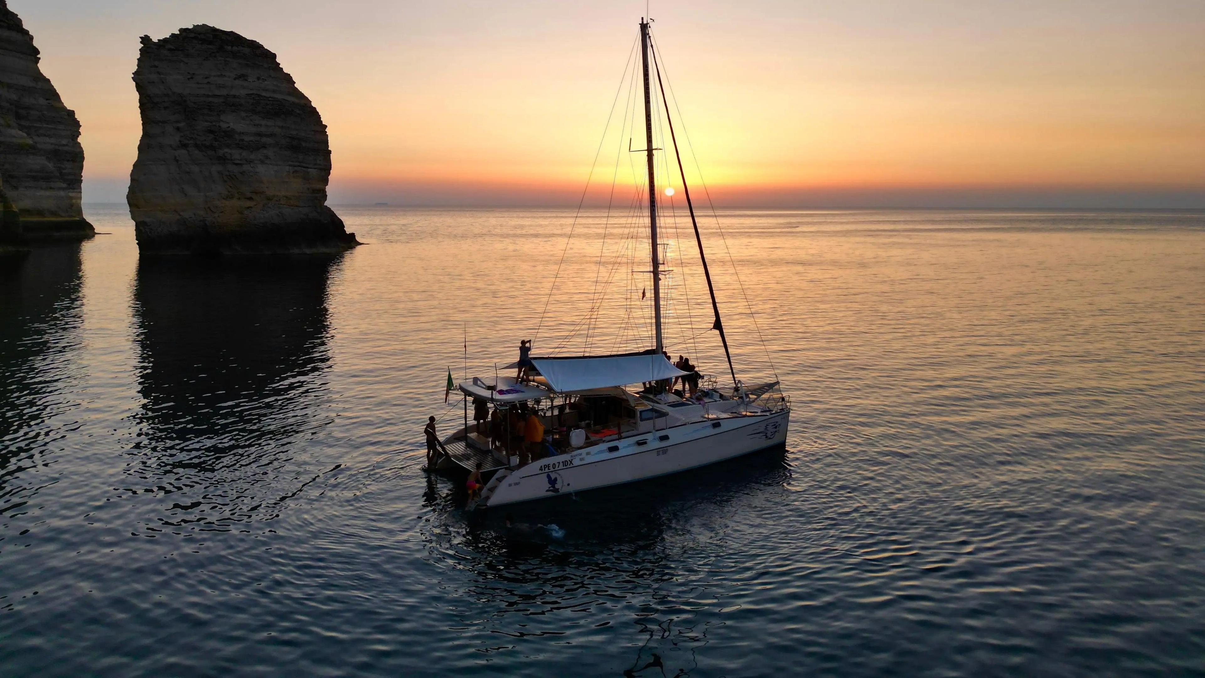 Onze catamaran vaart bij zonsondergang.