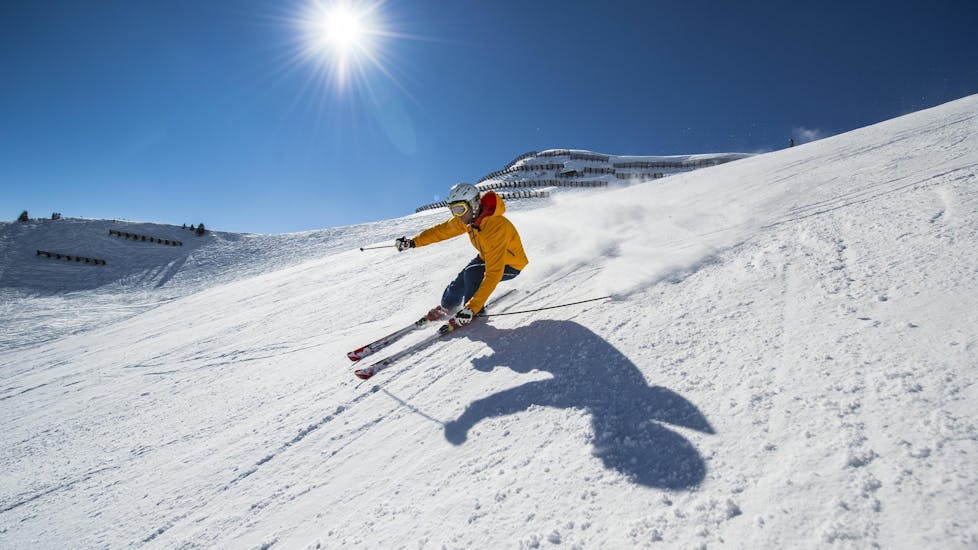 Private Ski Lessons for Adults of All Levels: A skier is skiing down a sunny ski slope while participating in an activity offered by Ski- & Snowboarding Kaprun Preghenella.