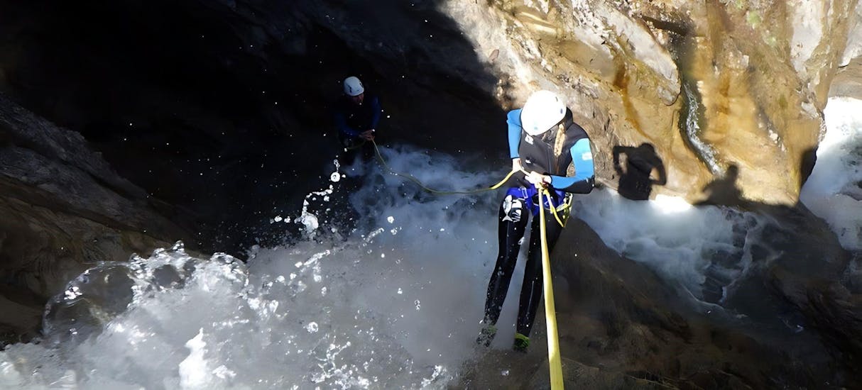 A woman abseiling a canyon with a waterfall.