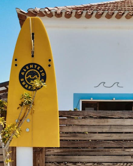 Una tavola da surf gialla con il logo della Alentejo Surf School a Vila Nova de Milfontes.