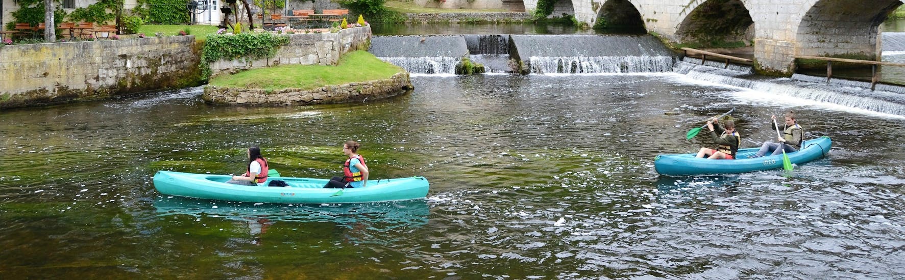 Friends are paddling on the Dronne river in the middle of the charming village of Brantome during their canoeing tour with Allo Canoes Dordogne.