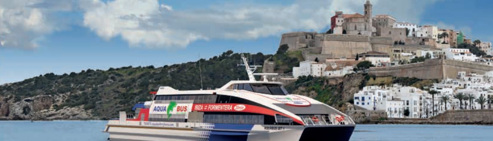 Boot von Aquabus Ferry Boats Ibiza mit Ibiza Stadt im Hintergrund.