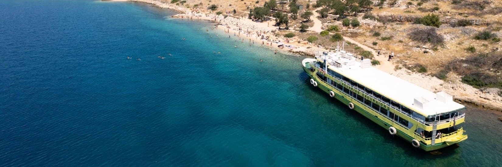 The boat of Aquarius Excursions Zadar in front of a beautiful beach during their boat tour.