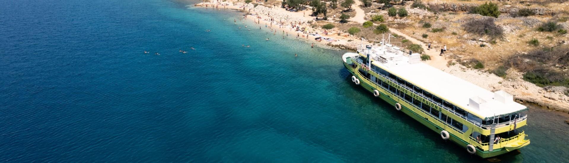 The boat of Aquarius Excursions Zadar in front of a beautiful beach during their boat tour.