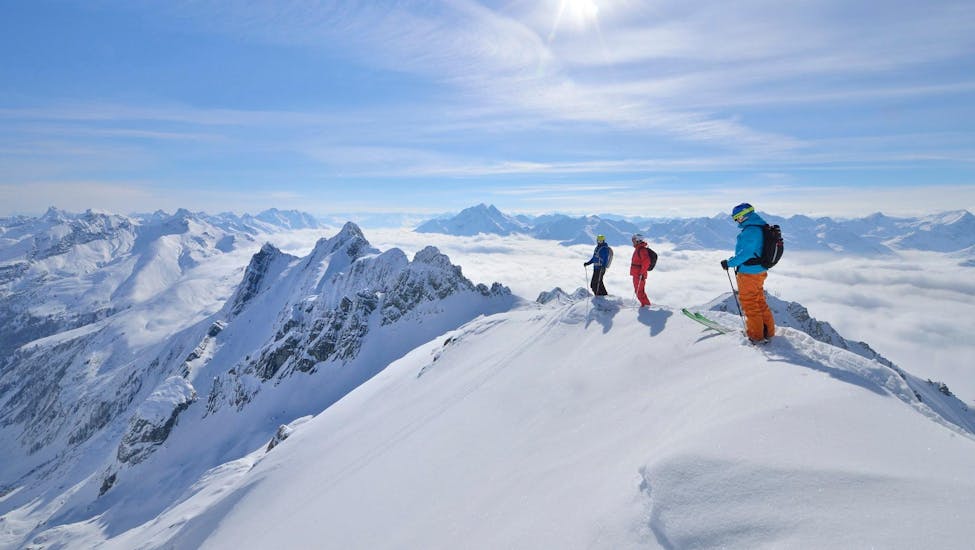 Tres esquiadores que participan en un Clases privadas de seguridad en nieve para todos los niveles de Herbert Lüthi observan desde la cumbre el maravilloso panorama invernal nevado