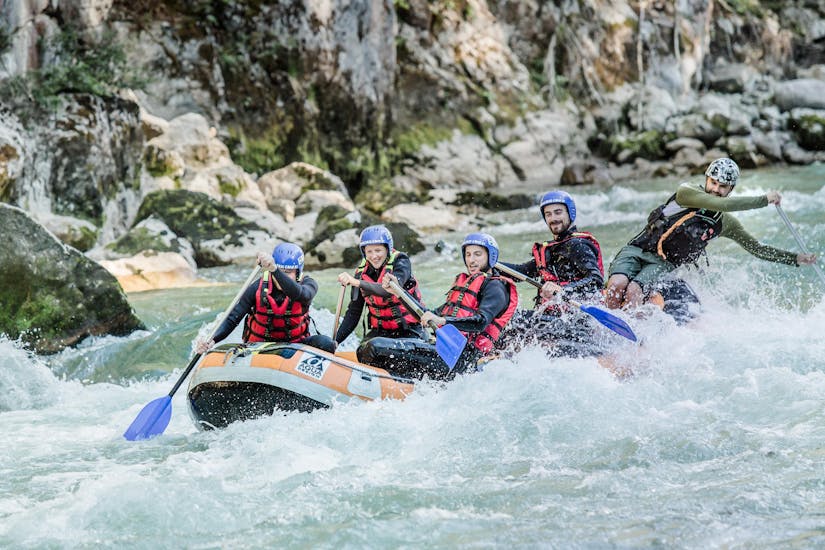A group of friends is paddling through the rapids of the river Saalach during a rafting tour in Lofer with Base Camp.
