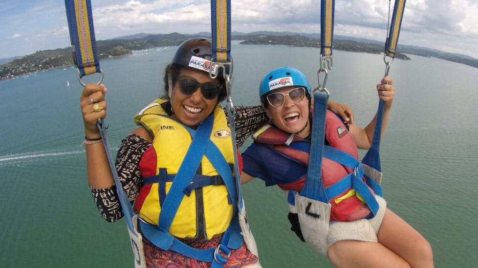 Two women are enjoying their parasailing flight above the Bay of Islands organised by Bay of Islands Parasail.