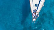 A family is sailing across clear blue waters on a vessel chartered from a boat rental.