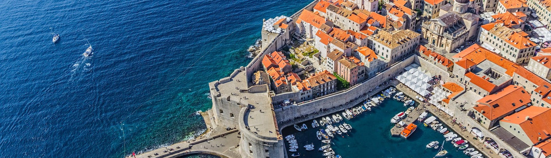 An aerial view of several boats anchored in the old port, a common departure point for boat tours in Dubrovnik.
