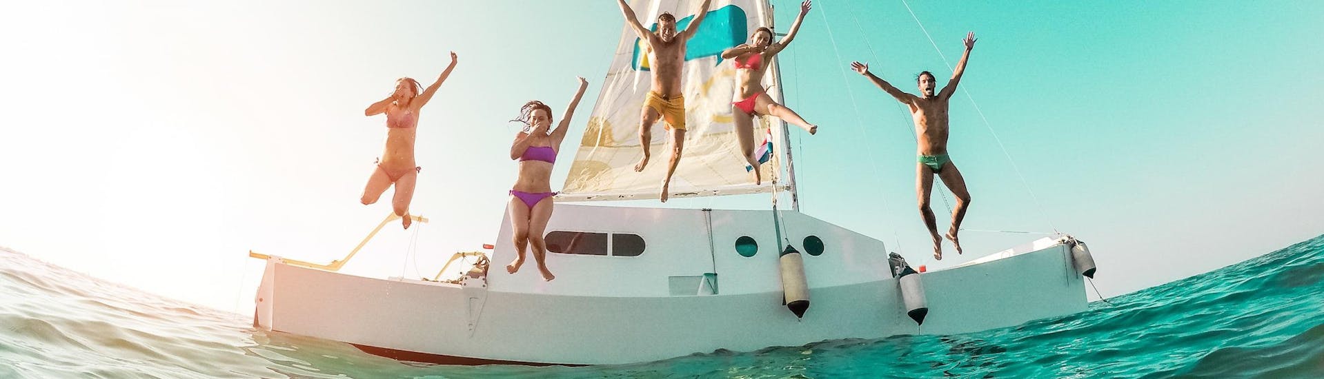 A group of friends is jumping into the sea during their boat trip in Ibiza.