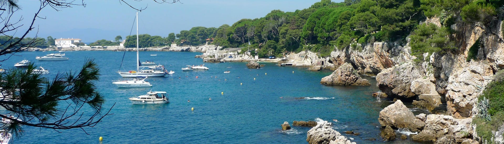 Boats are anchored in a quiet bay of Cap d'Antibes which can be admired during a boat trip from Juan-les-Pins.