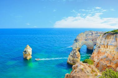 Ein Blick über die wunderbaren blauen Gewässer und die eindrucksvollen Felsformationen an der Algarve, die Besucher bei einer Bootstour von Lagos zu sehen bekommen.