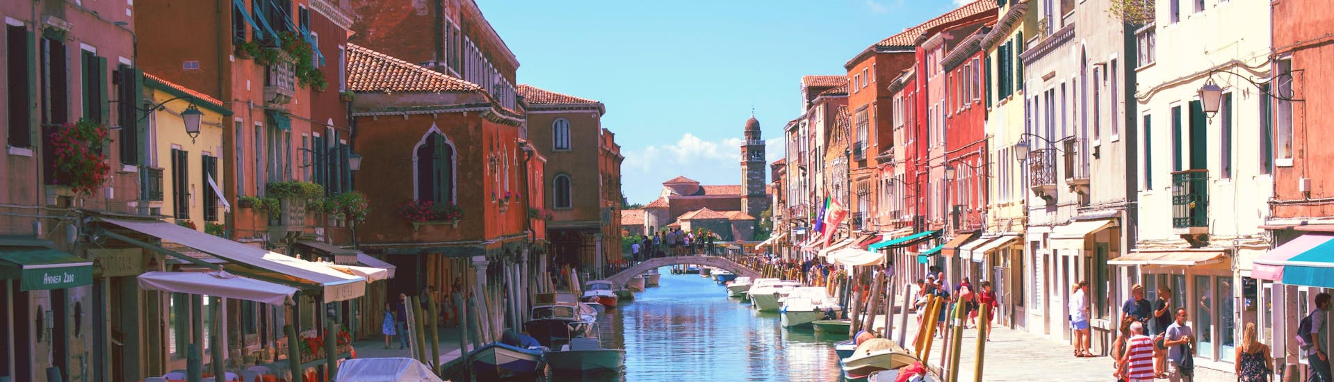 A gondoliere is paddling the boat through a narrow canal on a gondola ride near Murano in Venice.