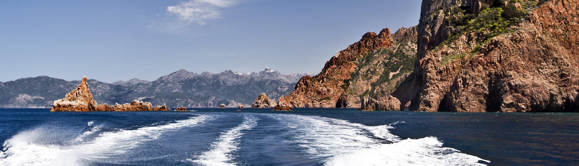 Blick vom Heck eines Bootes während einer Bootstour von Cargèse zu den beeindruckenden Calanques de Piana an der Westküste Korsikas.