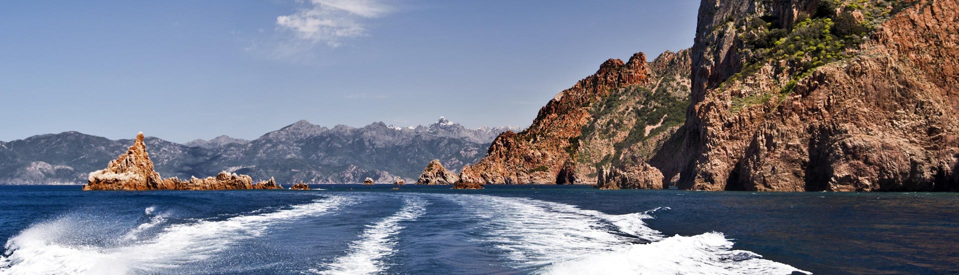 Vue de l'arrière d'un bateau lors d'une balade en bateau vers l'impressionnant Capo Rosso sur la côte ouest de la Corse.