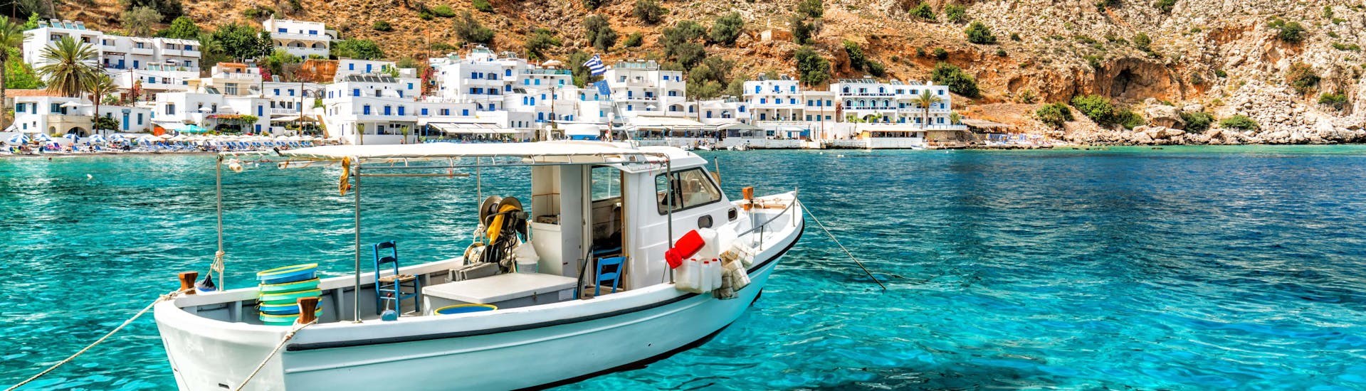 A boat on the crystal clear water in front of the coast of Crete, a popular destination for boat trips. 