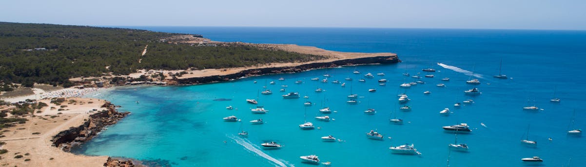 Gite in barca a Cala Saona SEM Hero Costa piena di barche durante una gita in barca a Cala Saona.