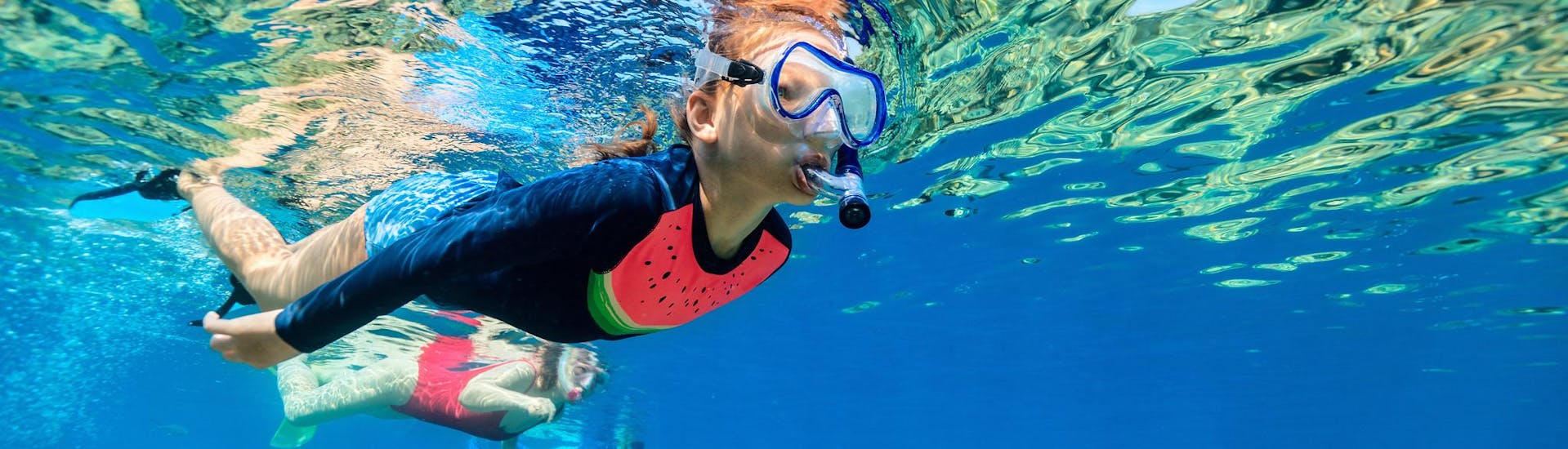 Kids enjoy snorkeling through their diving goggles during a boat trip