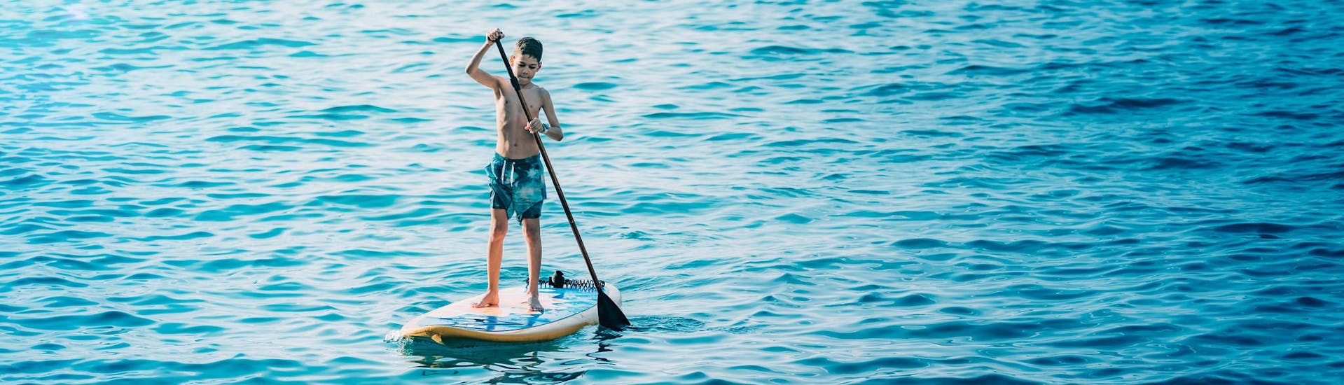 A kid on a board during a boat rental activity with SUP boards included on board.
