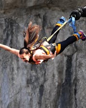 Eine junge Frau hält den Atem an während sie sich beim Bungee Jumping in Valgadena in die Tiefen stürzt.