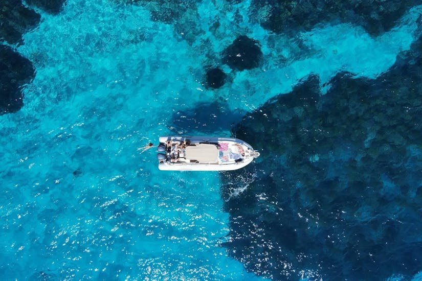 One of Egadi Charter & Tour's boats in the crystal-clear waters, seen from above.