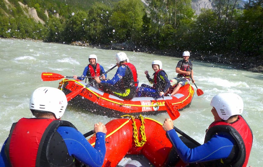 A group of friends is having fun during a rafting tour on the Inn river with CanKick Ötztal.