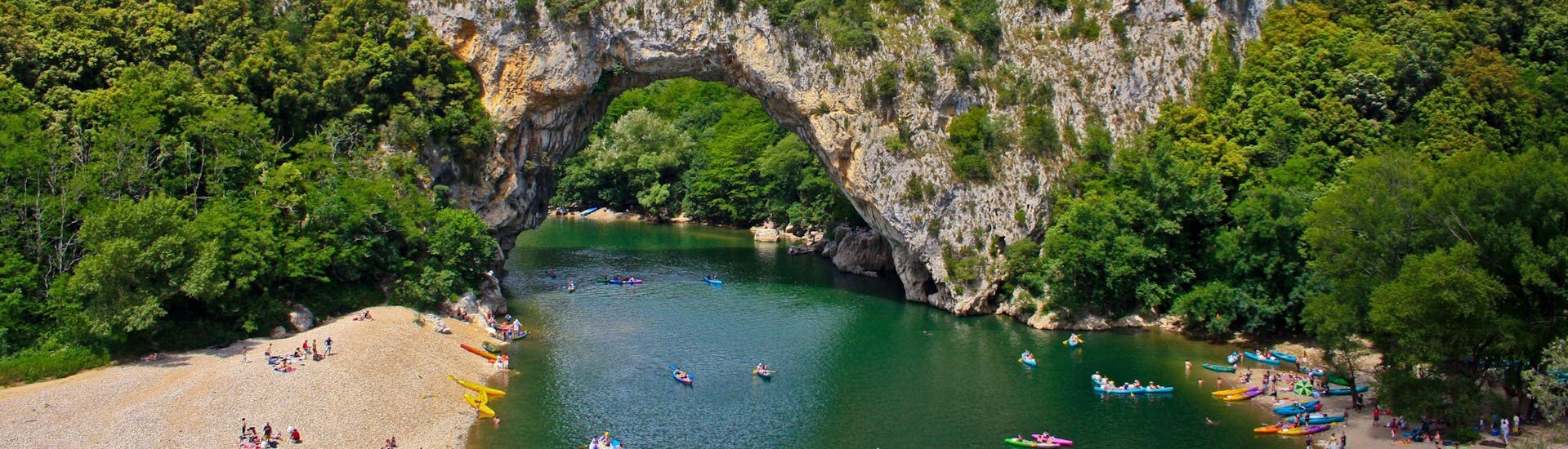 A mother and her two children are paddling across the water as they enjoy their kayak canoe in Gorges de l'Ardèche.