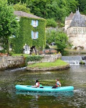 Des amis pagayent sur la Dronne au milieu du charmant village de Brantôme pendant leur circuit de 4 km en canoë avec Allo Canoës Dordogne.