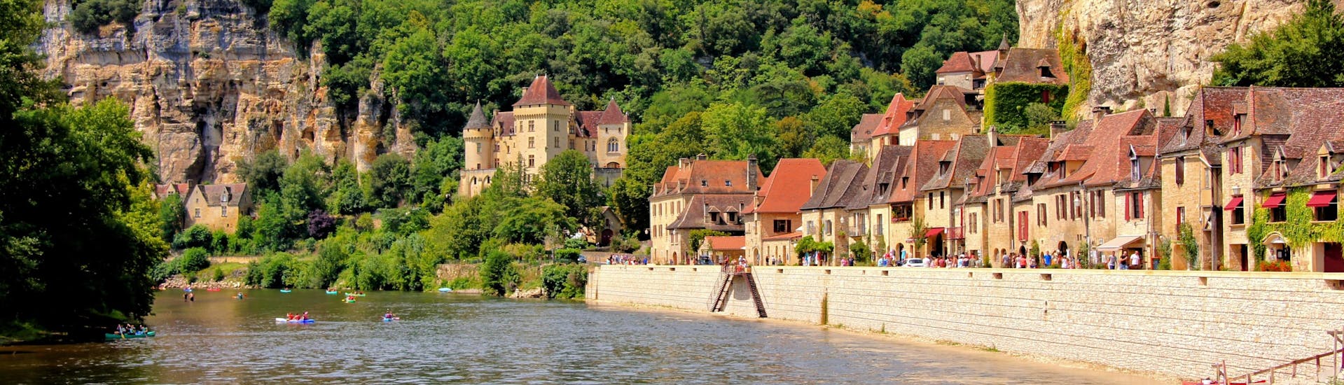 Beautiful view of the village of La Roque-Gageac on the Dordogne River on which tourists do canoeing during summer.