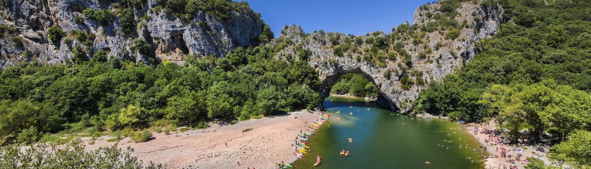 canoeing-vallon-pont-d-arc_SEM-Resort-Hero1 Einige Leute paddeln beim Kanufahren in Vallon-Pont-d'Arc durch berühmten steinernen Bogen.