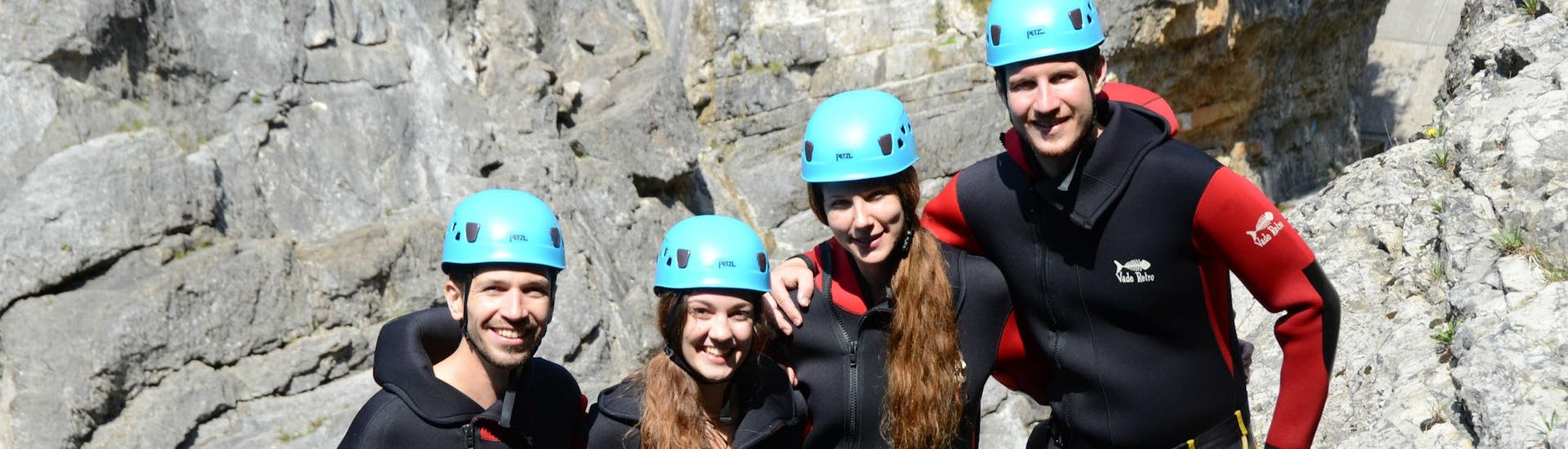 A group of friends is posing for a group photo while on a canyoning tour.