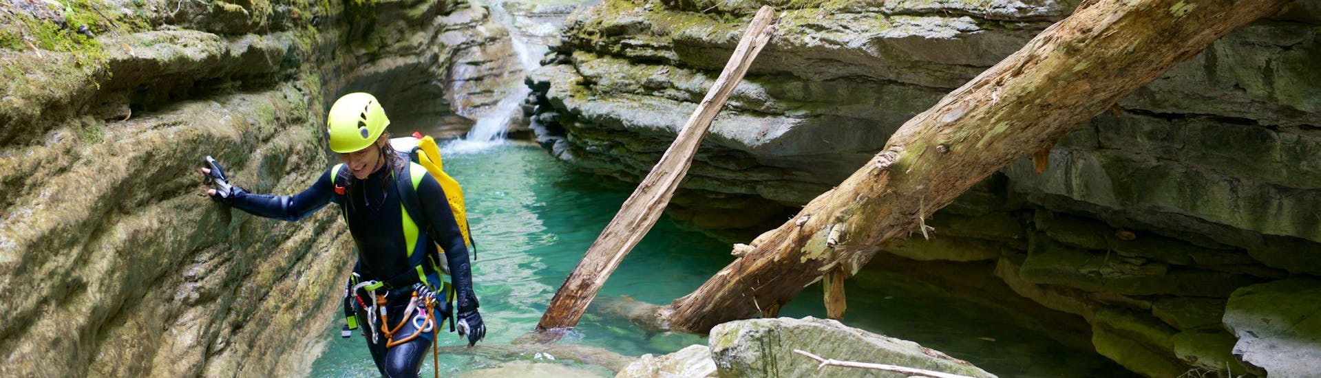A female canyoneer is wading through a natural pool of water while canyoning near Queenstown.