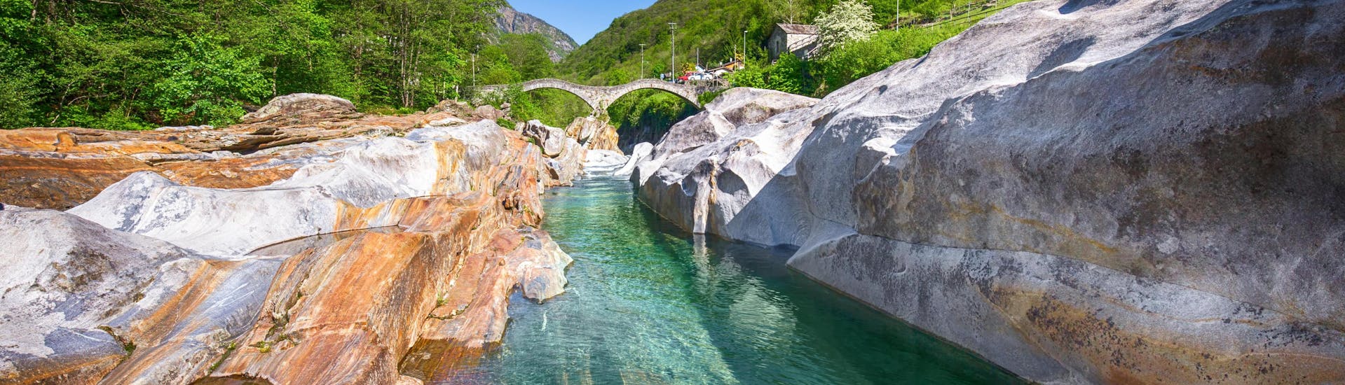 An image of a crystal clear stream flowing through the Verzasca Valley, a popular destination to go canyoning in Ticino.