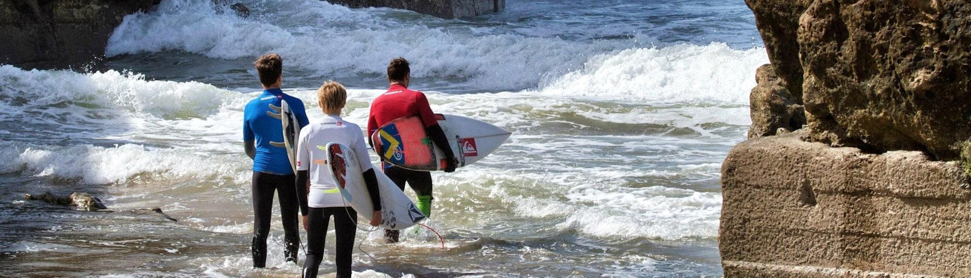 Trois surfeurs se dirigent vers la mer pour leurs cours de surf avec Capbreton Surfer School.